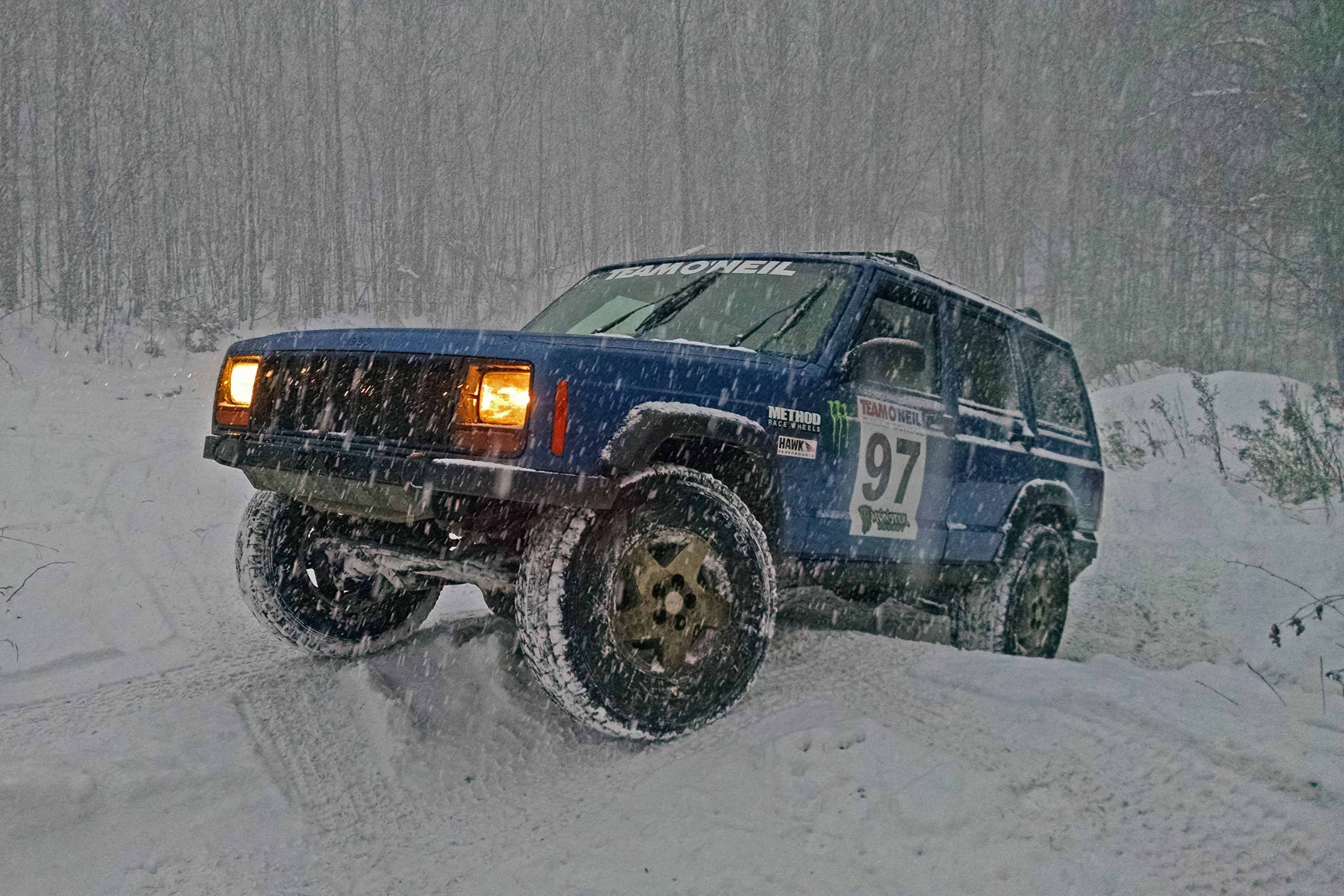 Jeep Cherokee climbing a steep, off-road hill in winter weather