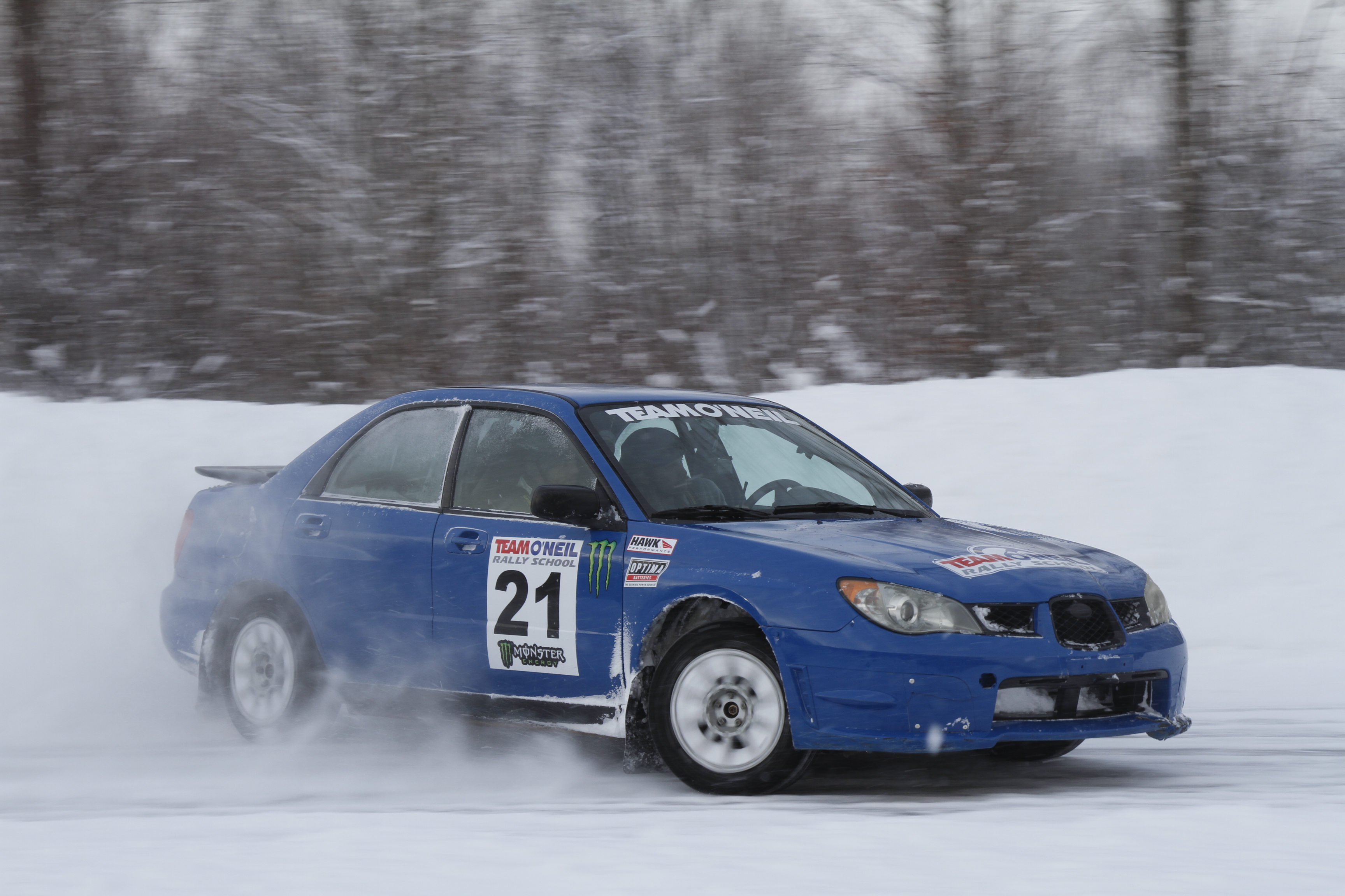 Blue Subaru sliding on icy roads at Team O'Neil Rally School showing tractionized tires.