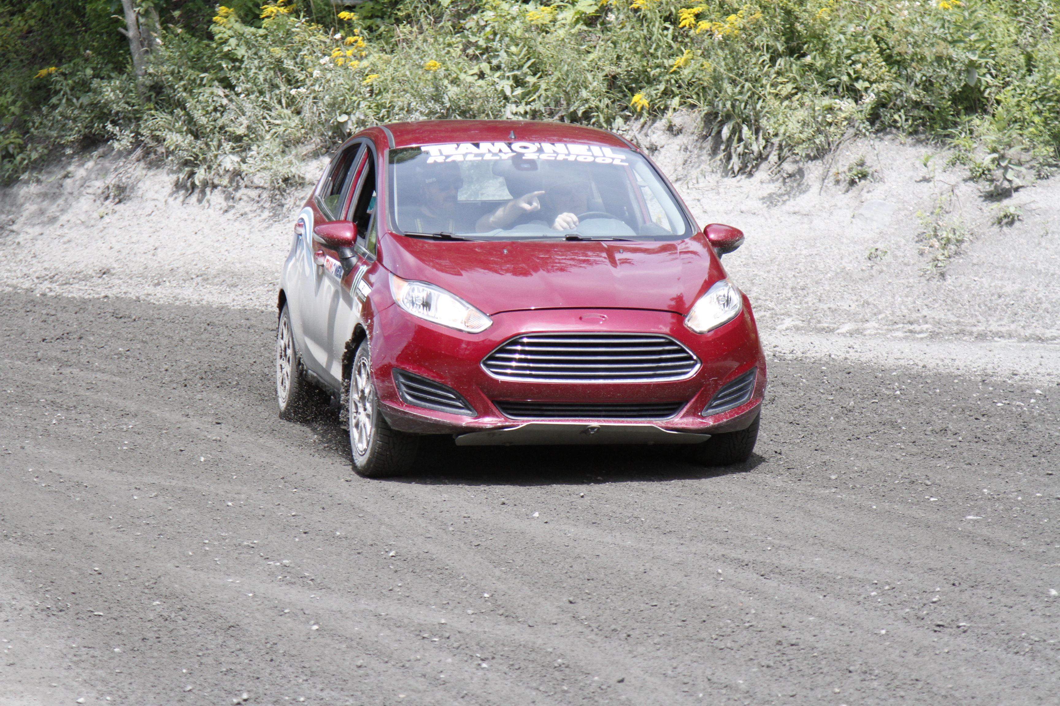 Ford Fiesta navigating a dirt rally road.